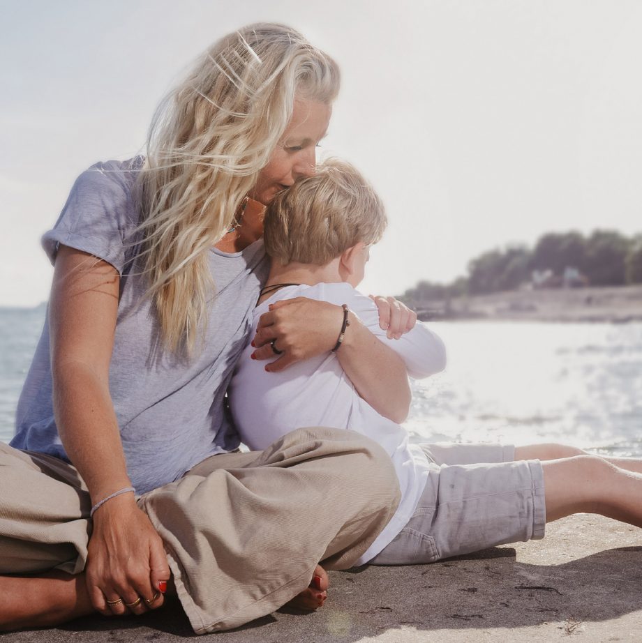 Caochin Kirsty sitzt am Strand mit ihrem Sohn, den sie innig im Arm hält und ihn küßt: