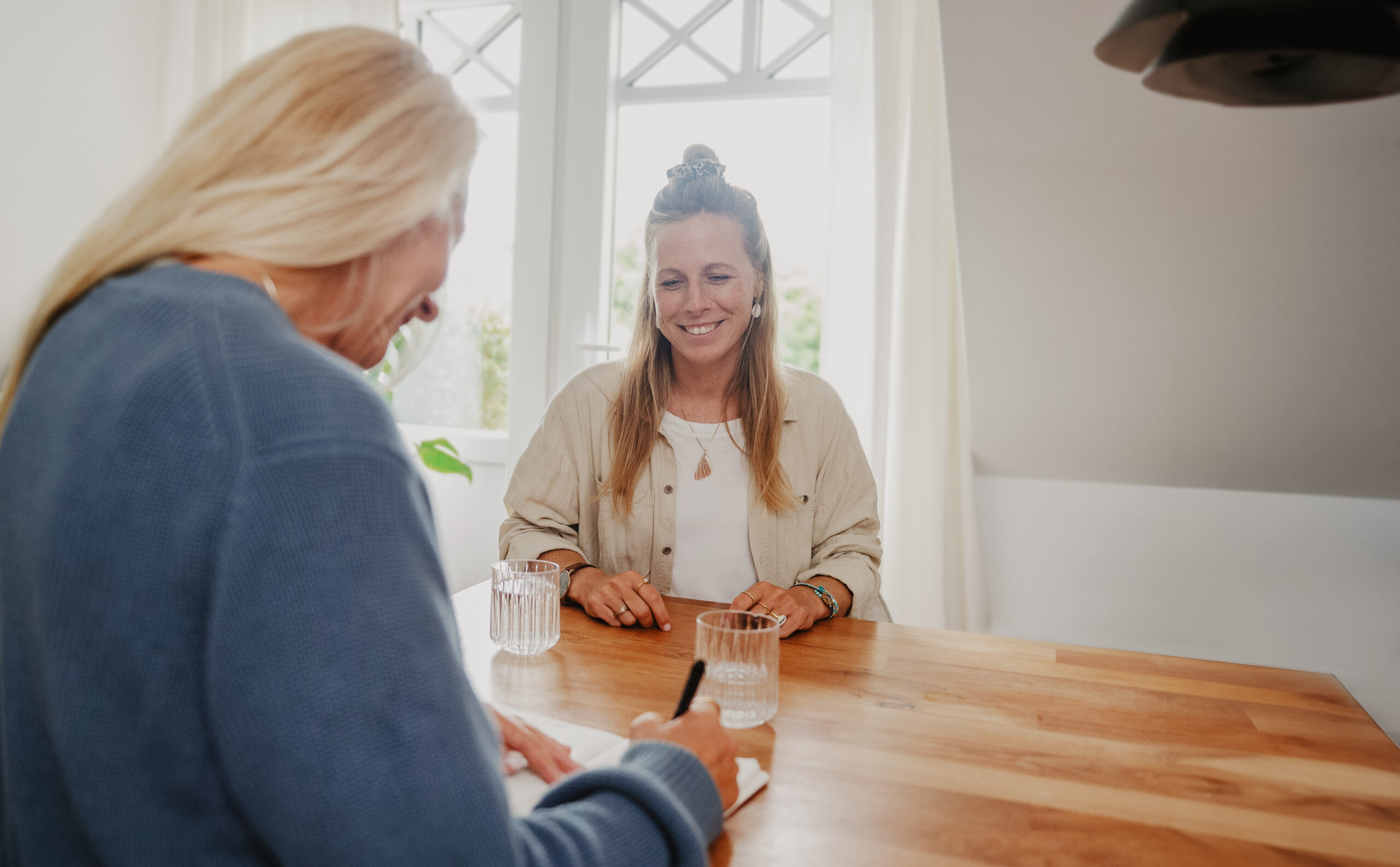 Coaching am Tisch mit Klientin die glücklich guckt