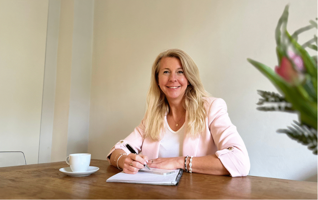 Ich sitze am Schreibtisch und schreibe auf einer Unterlagen. Glücklich und freundlich.