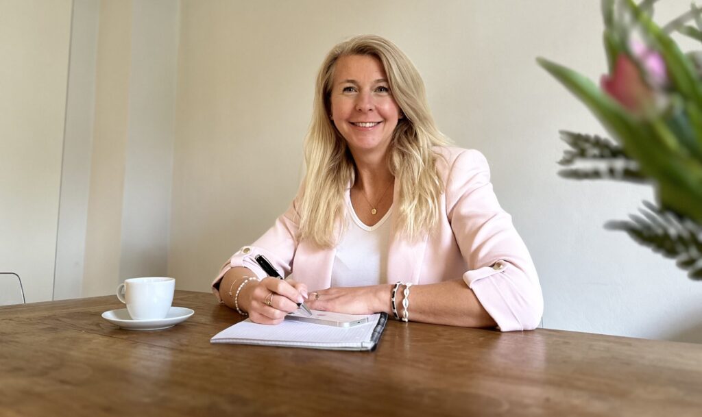 Ich sitze am Schreibtisch und schreibe auf einer Unterlagen. Glücklich und freundlich.